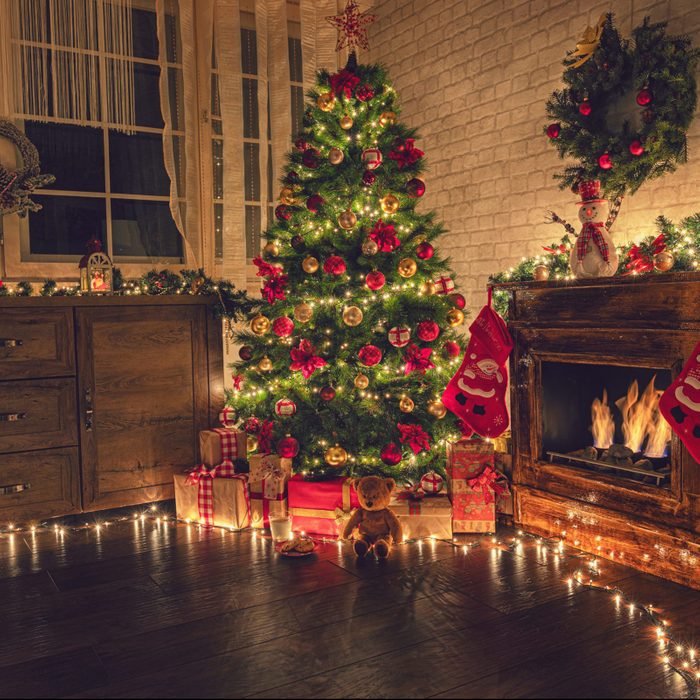 Christmas tree near fireplace in decorated living room