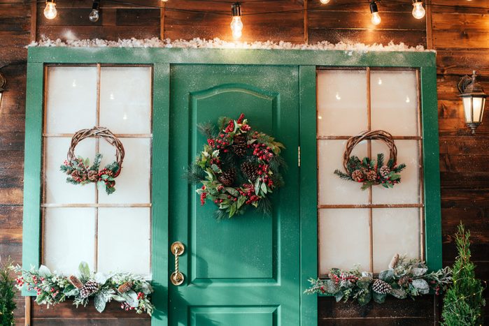 Porch with wooden doors and a threshold with Christmas decor.