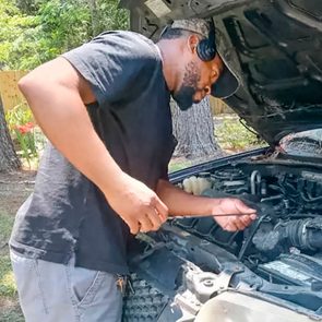 Eliot Middleton working on a car; looking at the engine of a car with its hood open