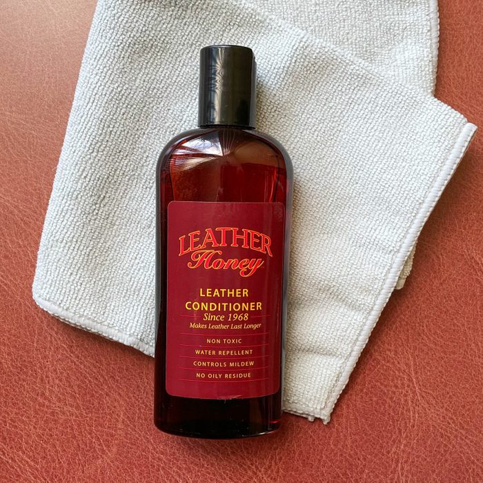 Leather Honey leather cleaner and folded gray mircofiber cleaning cloth on reddish-brown leather texture background
