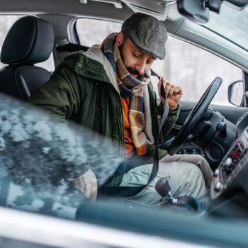 man warming up his car in the winter