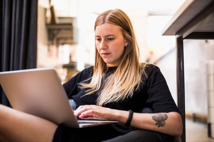 Young businesswoman using laptop while sitting on bean bag in small office