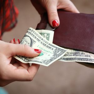 close up of hands, one holding a wallet, the other holding a folded dollar bill for a tip