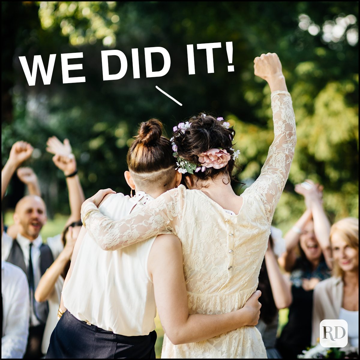 Young lesbian couple celebrating their marriage in front of their friends. The wedding ceremony is outdoors