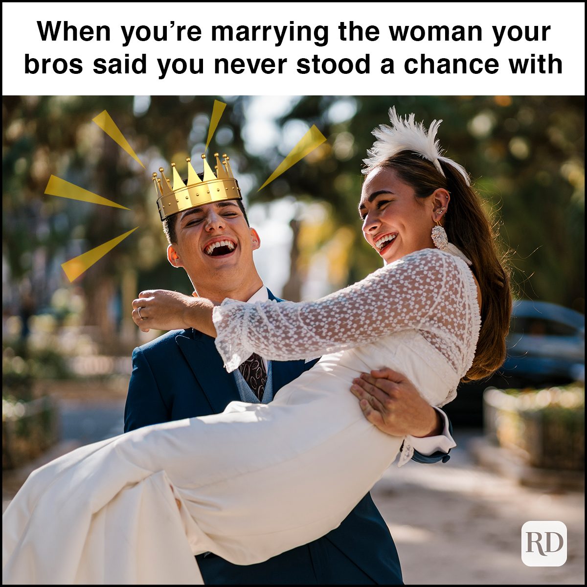 Bride laughing while carrying groom in park on sunny day