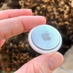 close up of hand holding an apple airtag outdoors