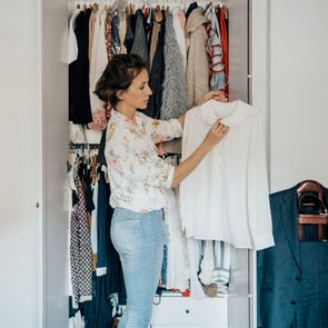 woman picking out blouse from wardrobe