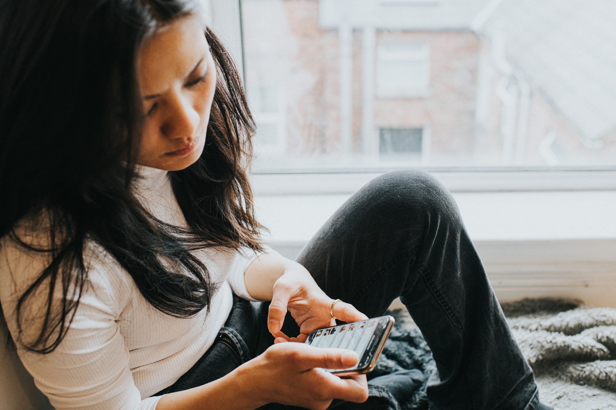 A perplexed woman checks her smart phone