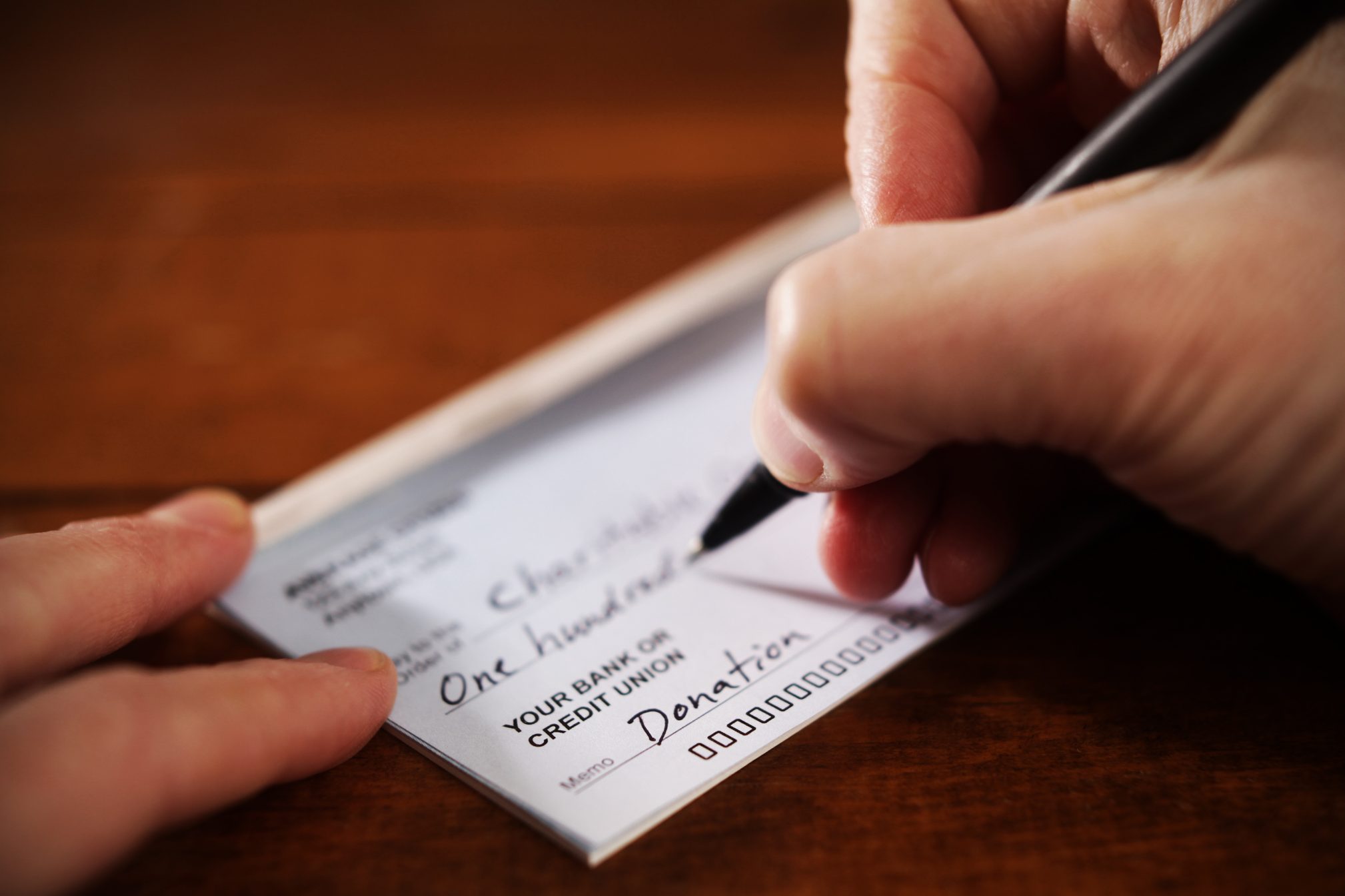 Close up View of Hand Writing A Donation Check