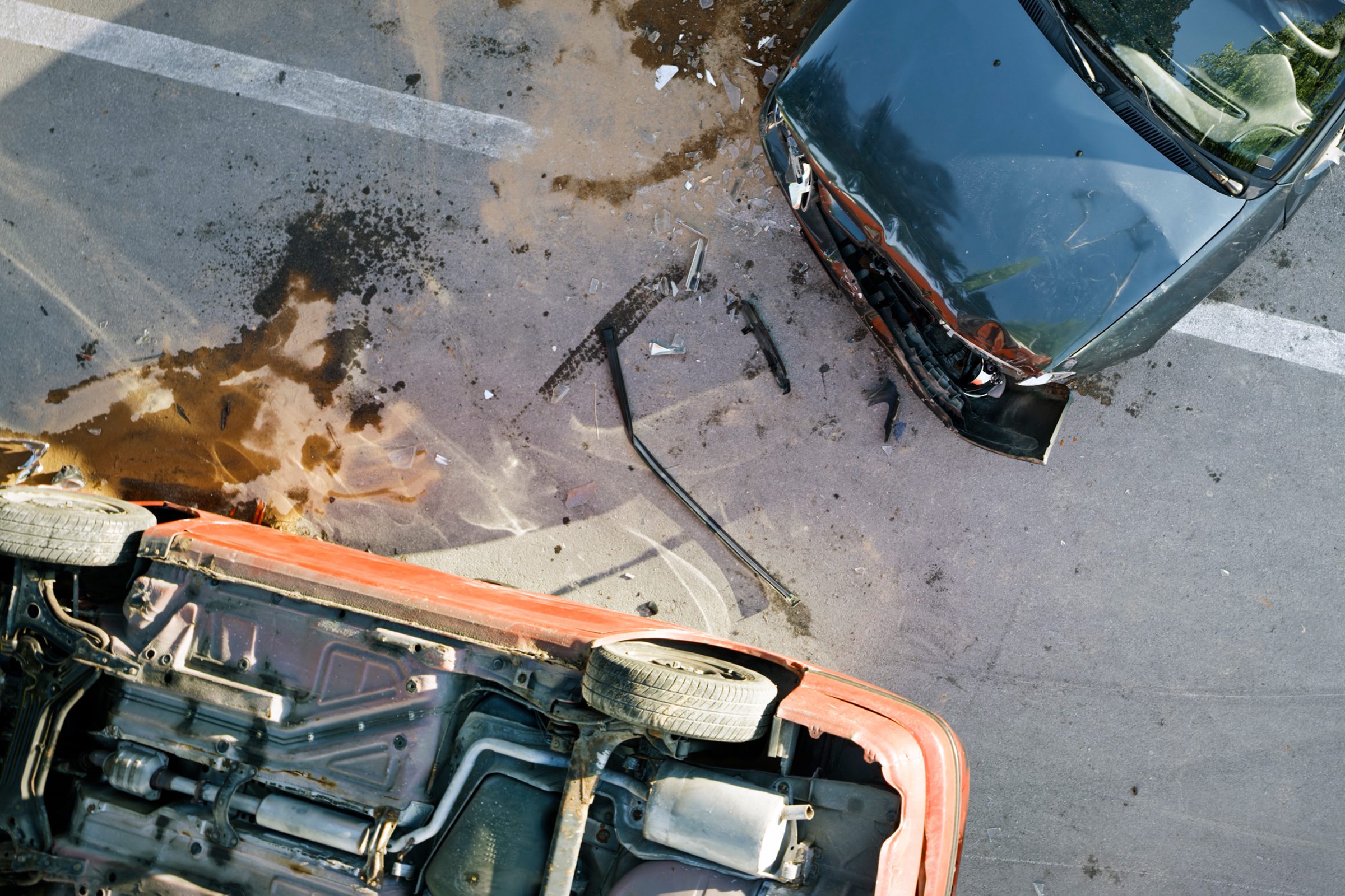 overhead view of two cars that have been in an accident, one car is upside down