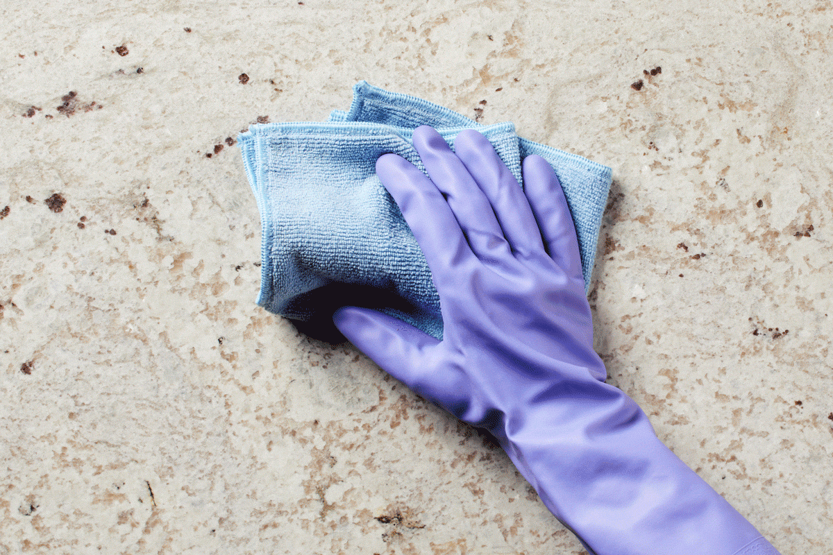 gif with gloved hand holding a cleaning cloth and the background changes between quartz, granit, marble, and wood kitchen counter textures