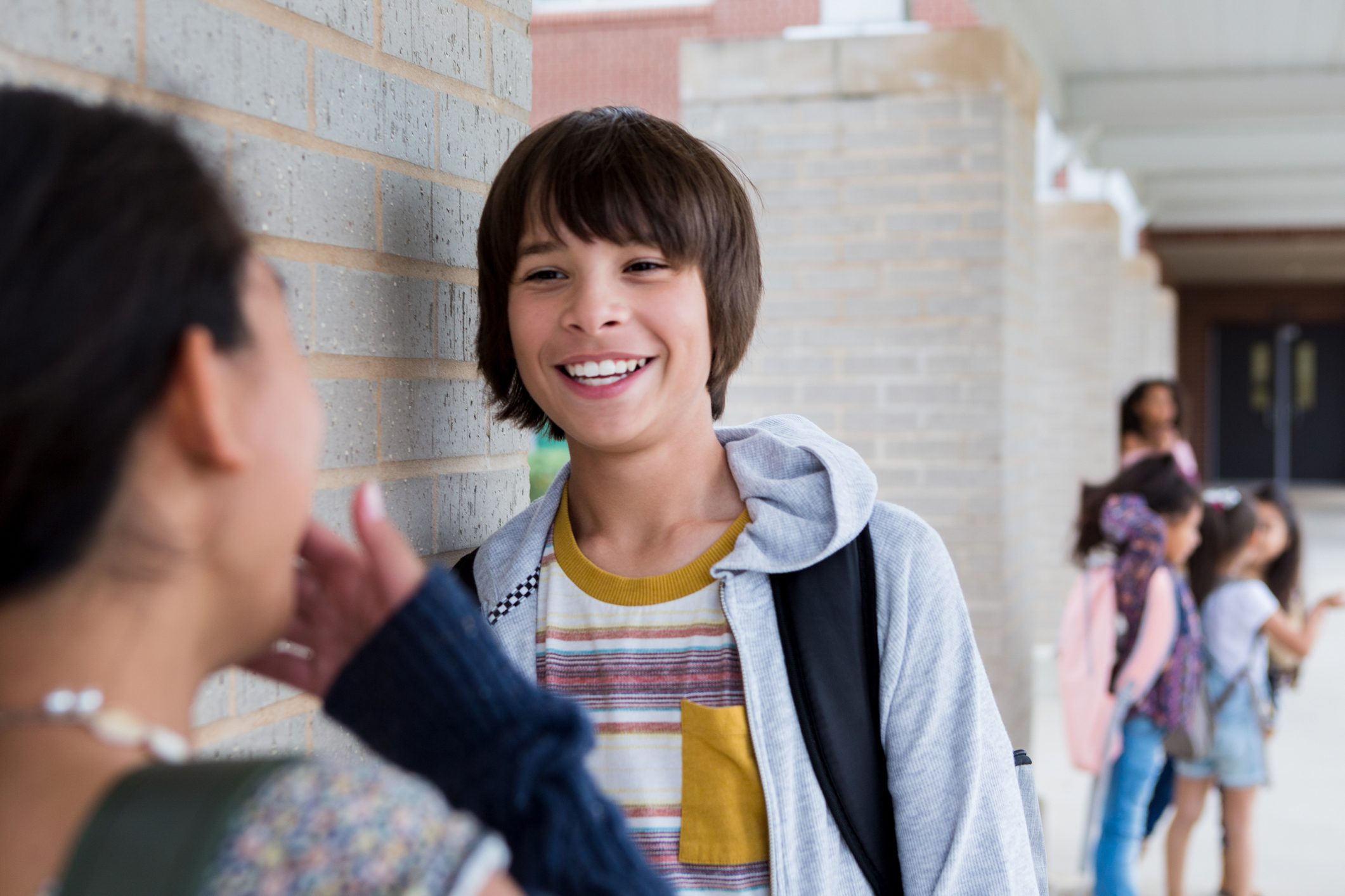 Middle school boy and girl laugh and talk after school