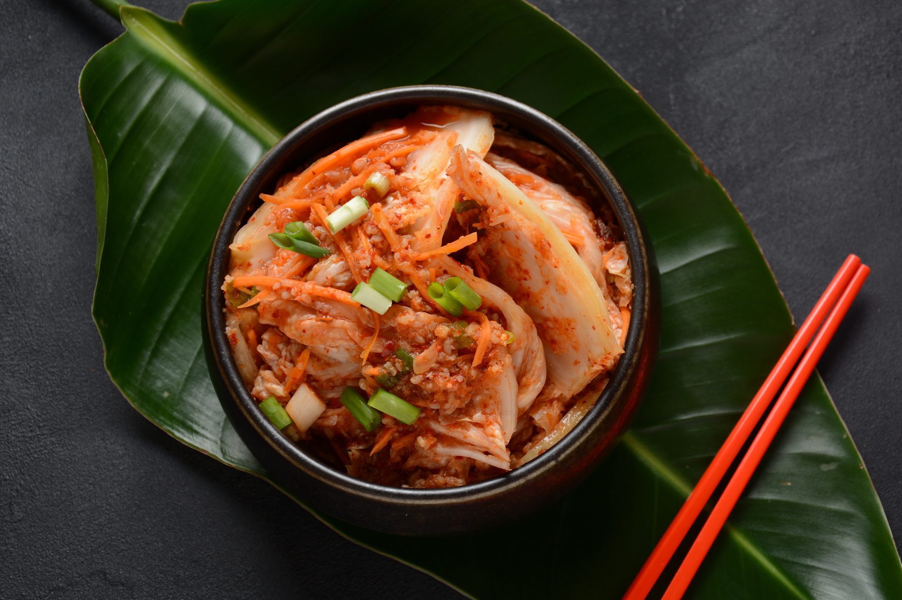 Kimchi and rice in black bowl with chopstick.