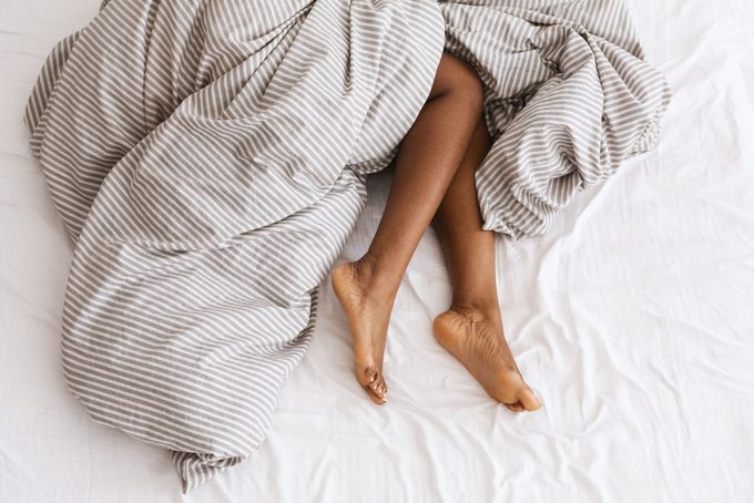 Slim, perfect and beautiful crossed woman legs on bed at vacation and holiday