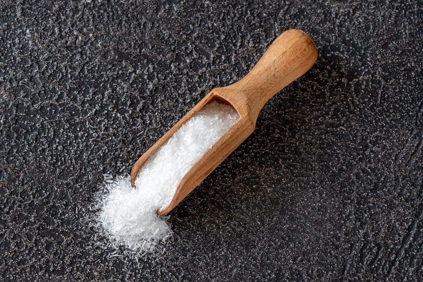 Wooden Scoop with Monosodium glutamate on black background