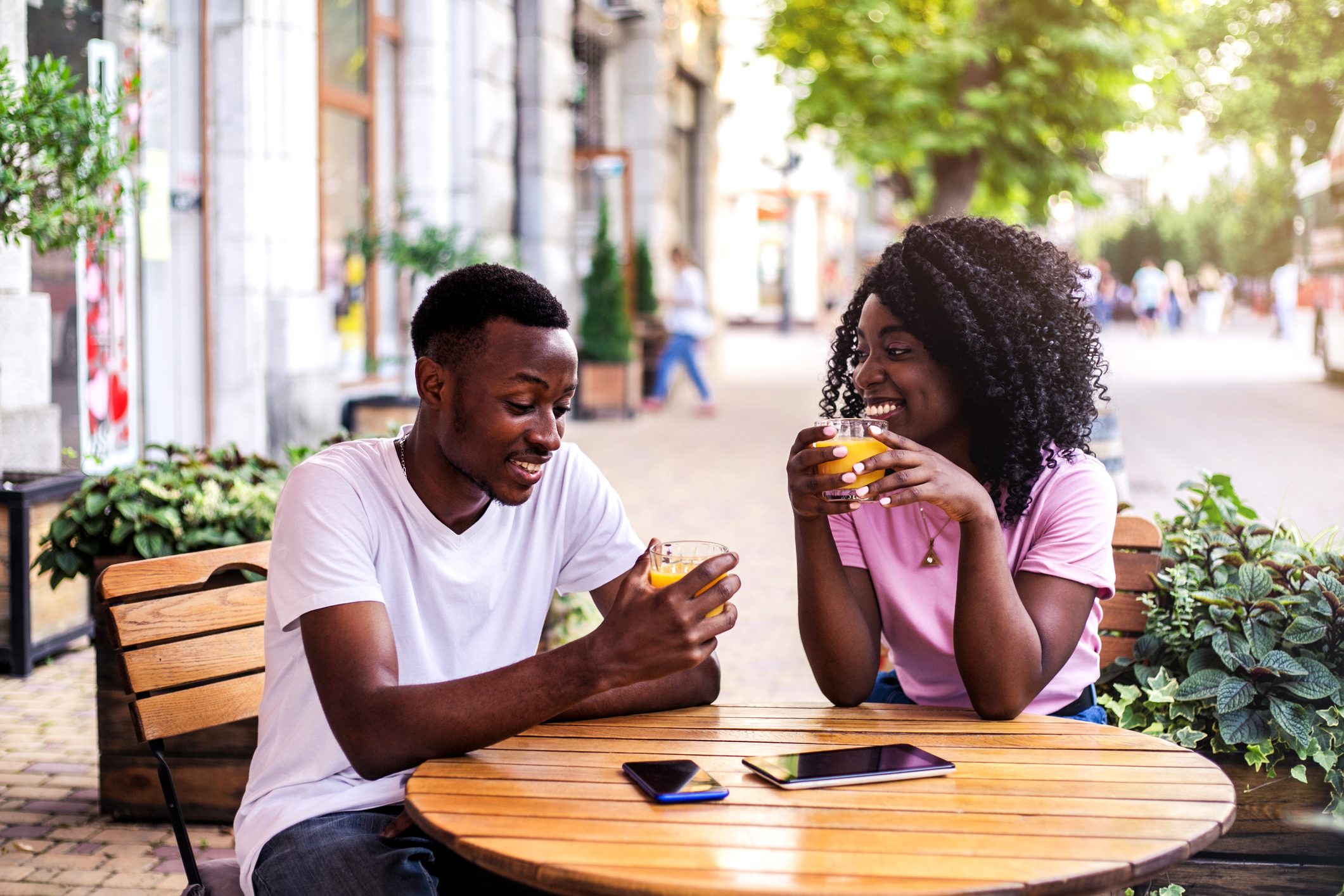 Portrait of stylish black couple at summer street cafe.