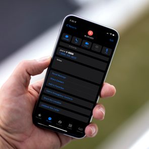 man holding an iphone with a blocked caller contact on it