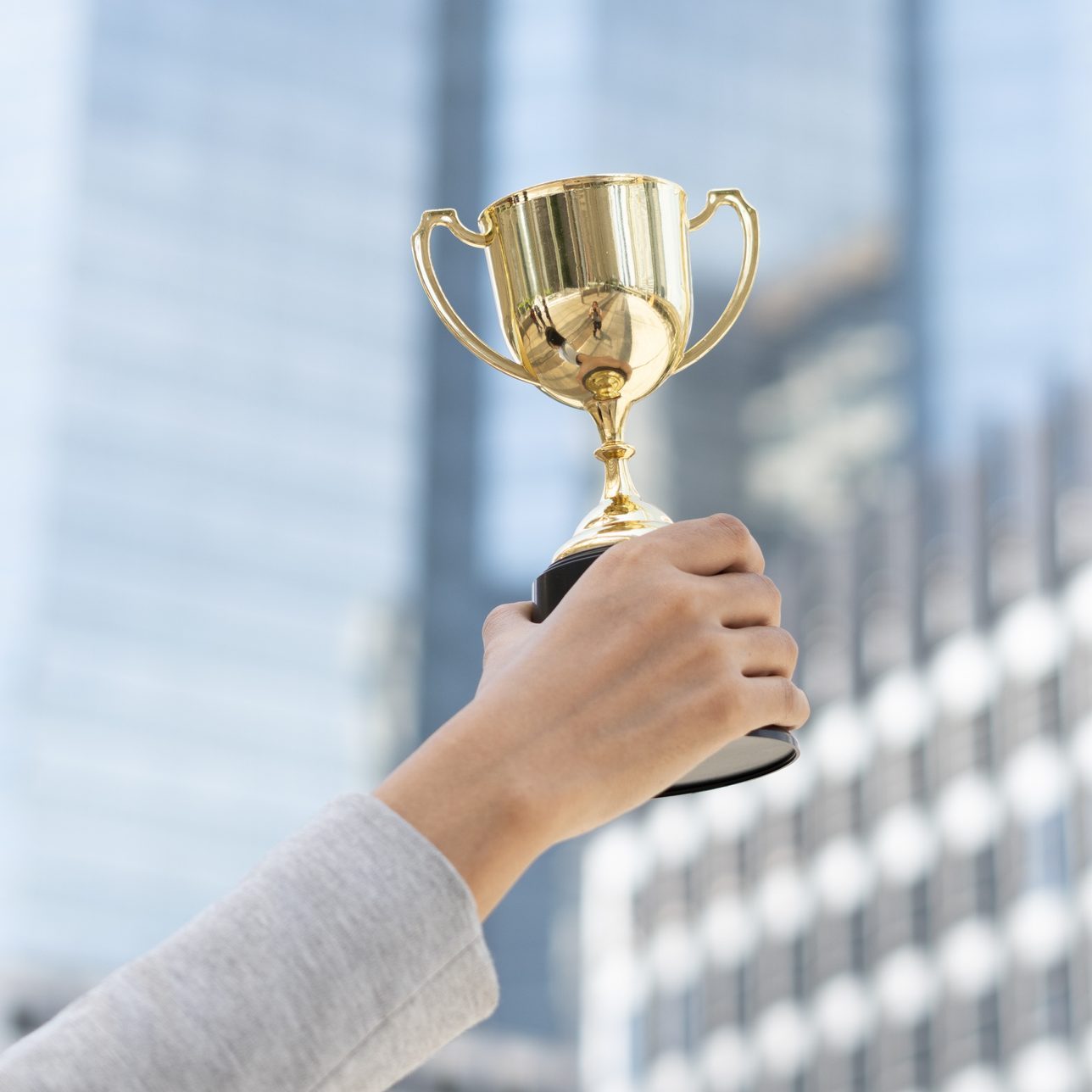 Business goals,Business concept.Close up hand of businesswoman holding gold trophy.
