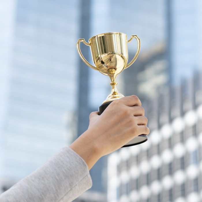 Business goals,Business concept.Close up hand of businesswoman holding gold trophy.