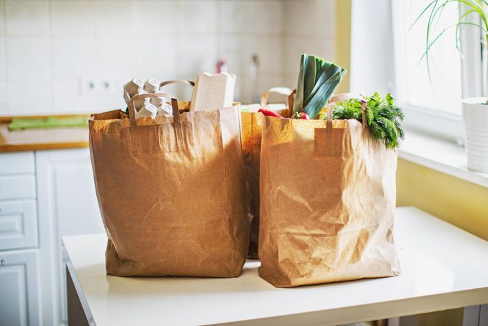 brown paper bags filled with groceries on a kitchen table