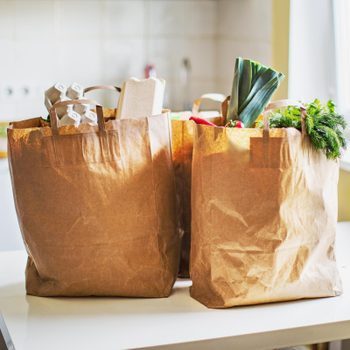 brown paper bags filled with groceries on a kitchen table