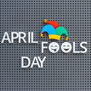 April Fools Day written on grey pegboard, jester hat decorates the lettering on gray background.