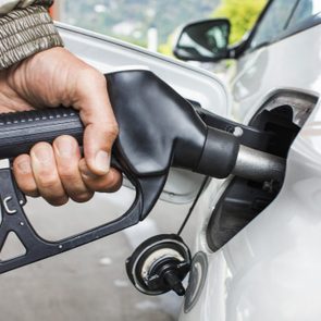 Mans's hand holding fuel nozzle in car