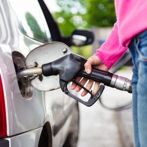 anonymous woman pumping gasoline fuel in car at gas station.