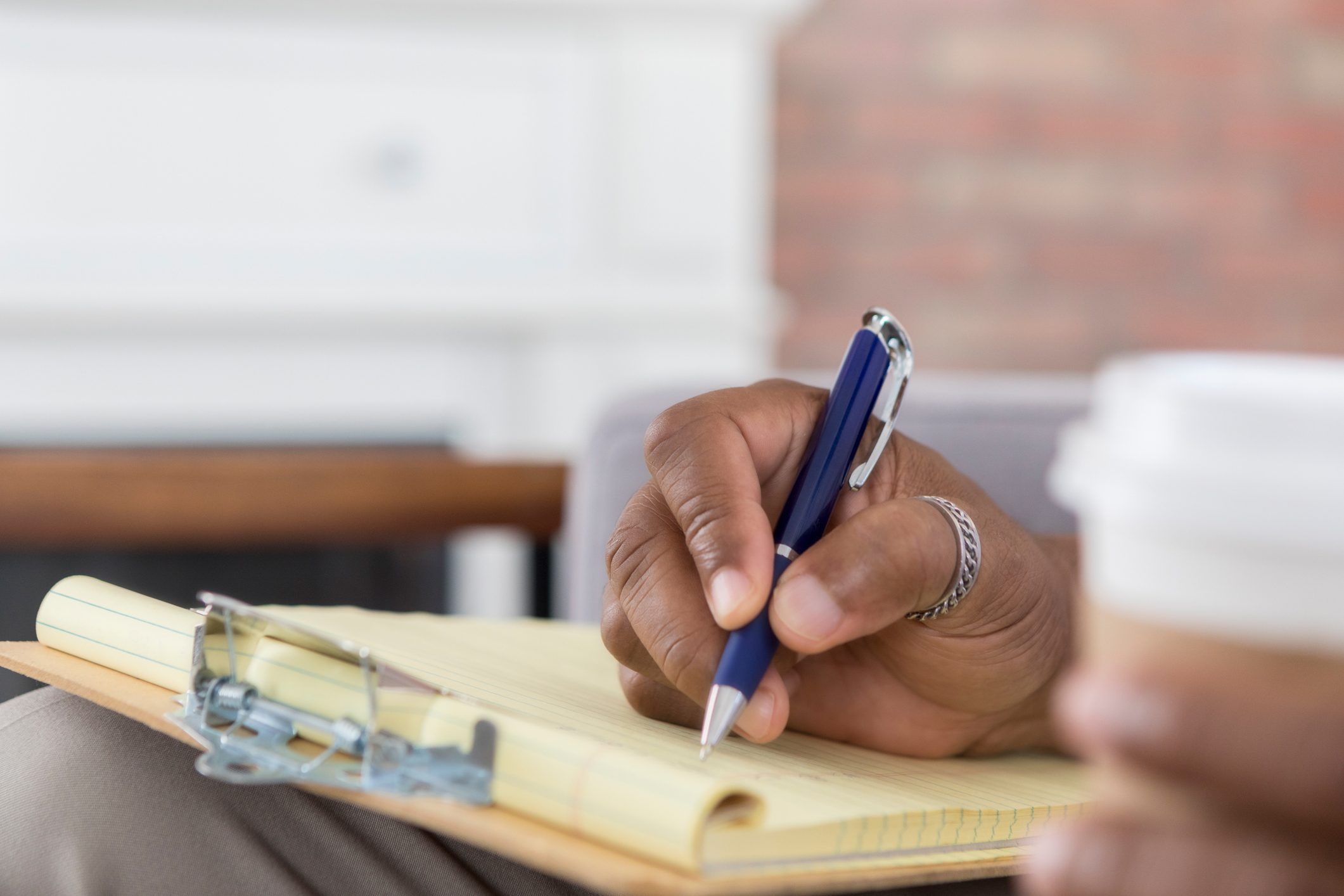 Closeup of unrecognizable person writing on clipboard