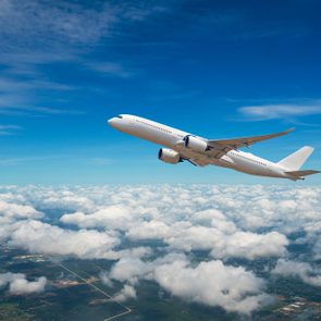 Commercial Airplane flying in clouds with civilization below