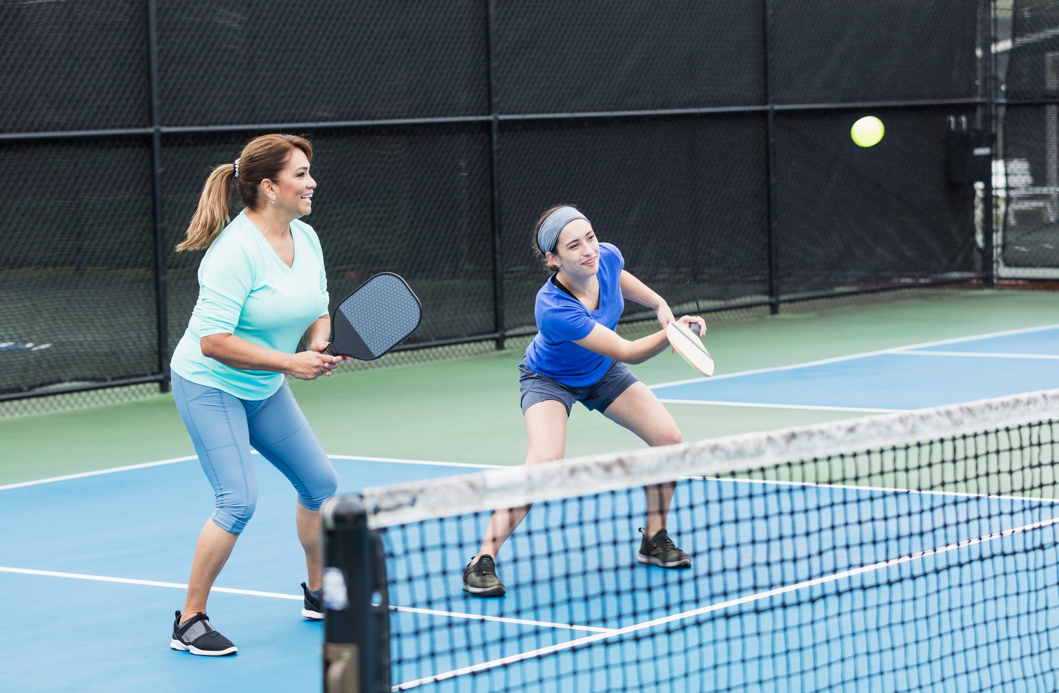 Hispanic woman and adult daughter playing pickleball