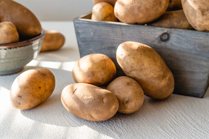 Raw organic potatoes close up on kitchen table, morning sunshine from the window
