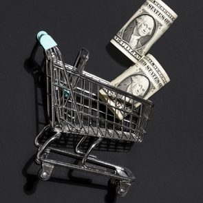 Shopping cart with dollar bills against black background