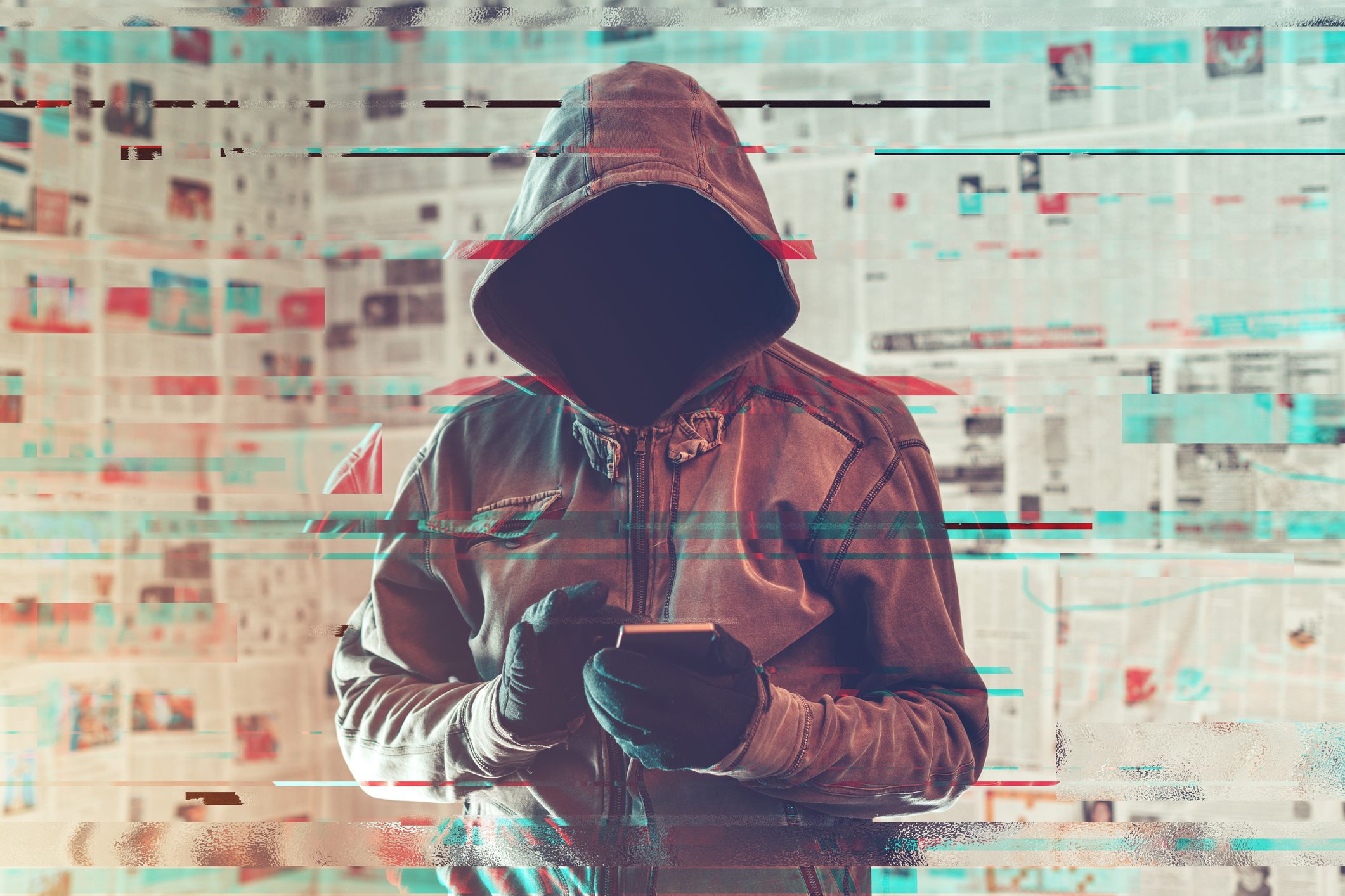 a hooded hacker person standing is using smartphone; the image is altered with a glitch effect