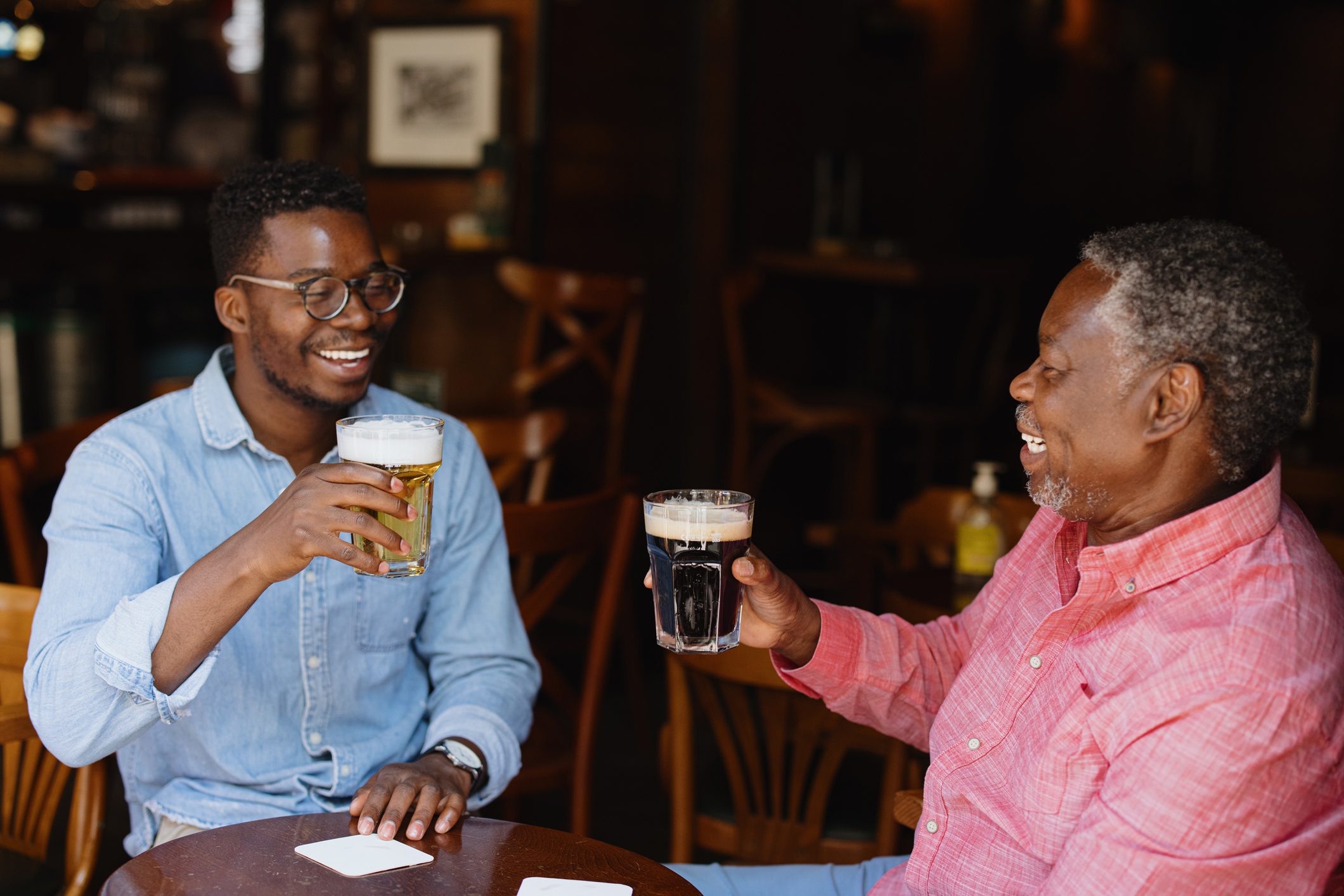 Father and son toasting and drinking beer in the pub