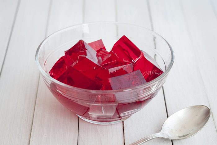 Red jelly cubes in glass bowl with silver spoon