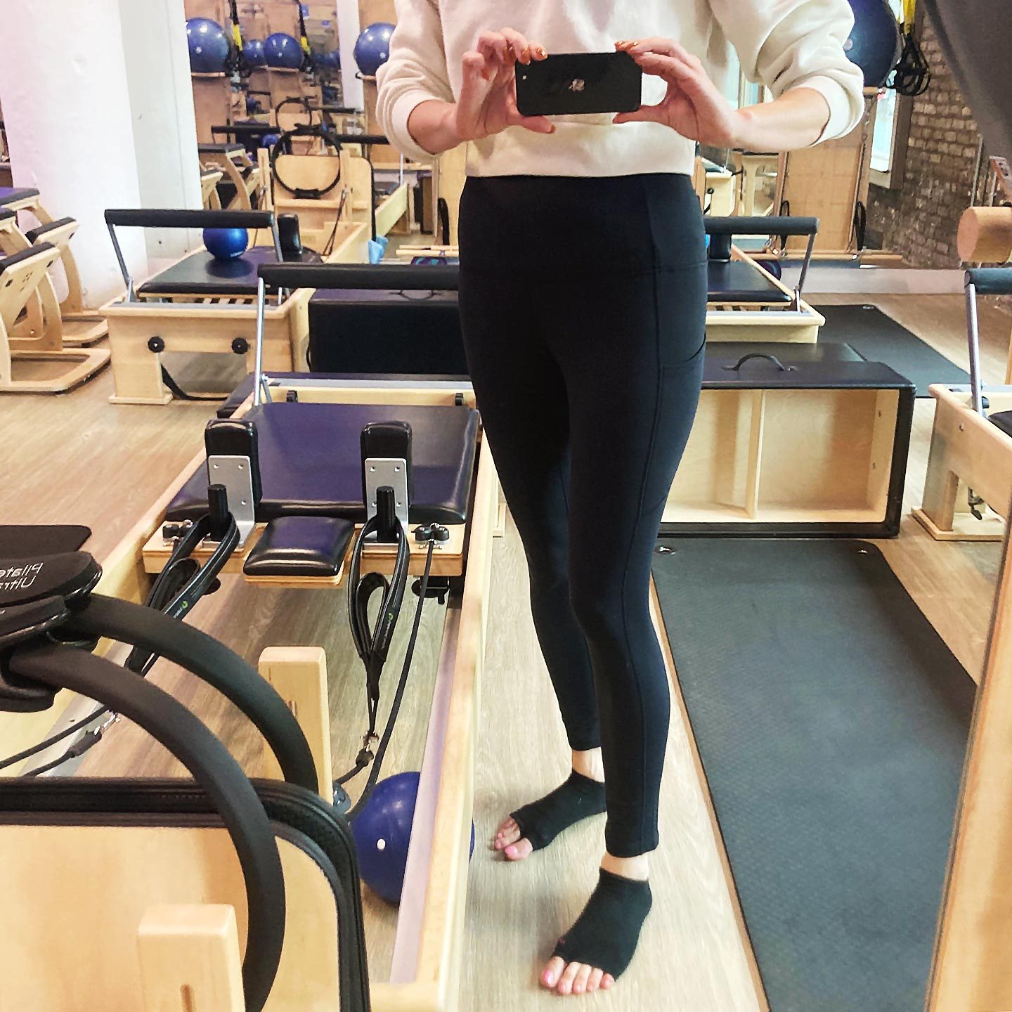 lower half of a woman in black leggings holding a phone