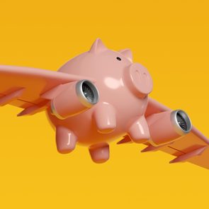 pink Piggy Bank with airplane wings on yellow background to illustrate budget airline concept