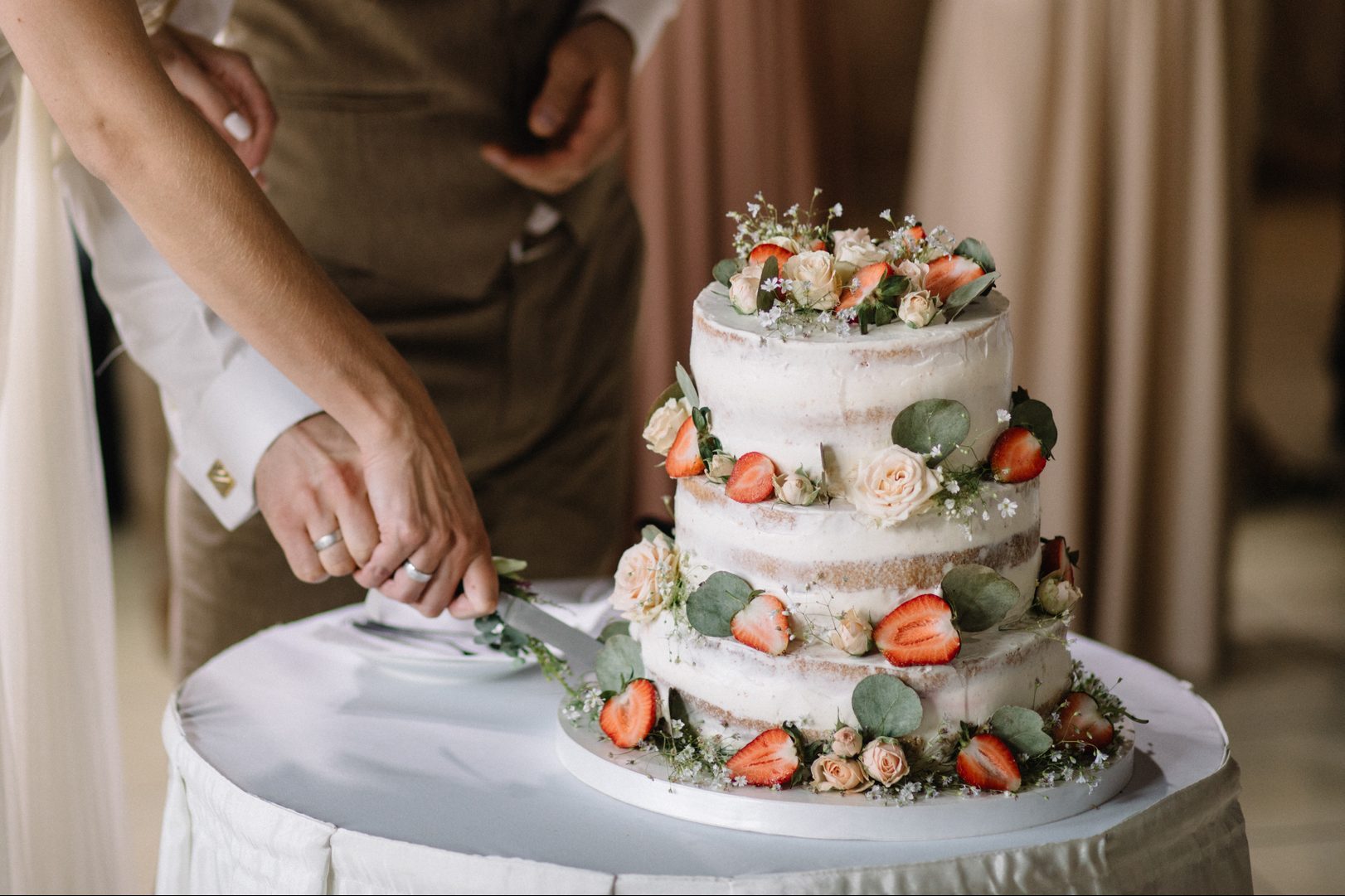 A bride and a groom is cutting their wedding cake