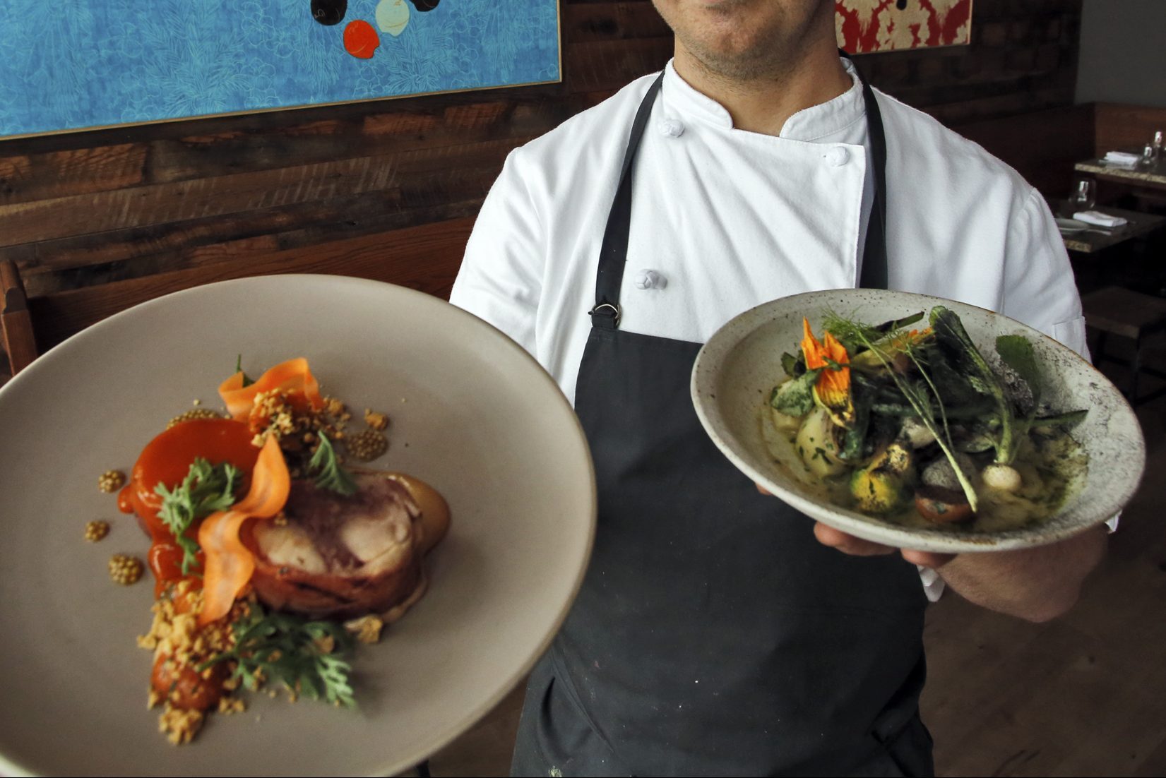 Chef Jim Christiansen holding rabbit dish, left, and veggie dish