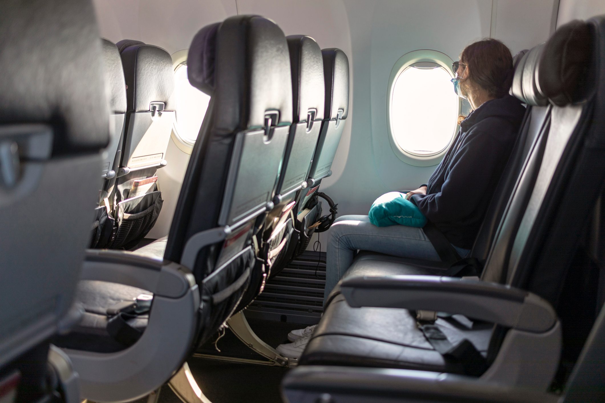 Air travel, passenger looking out airplane window, empty seats, COVID-19