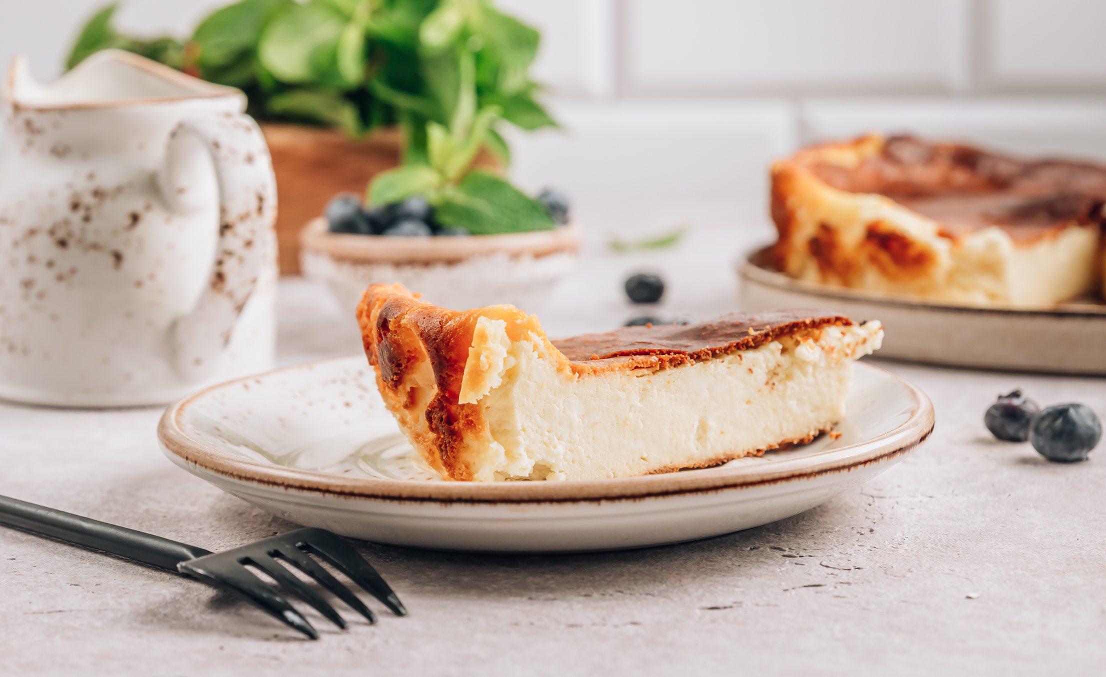 A piece of Basque burnt cheesecake with the whole cake is at the background