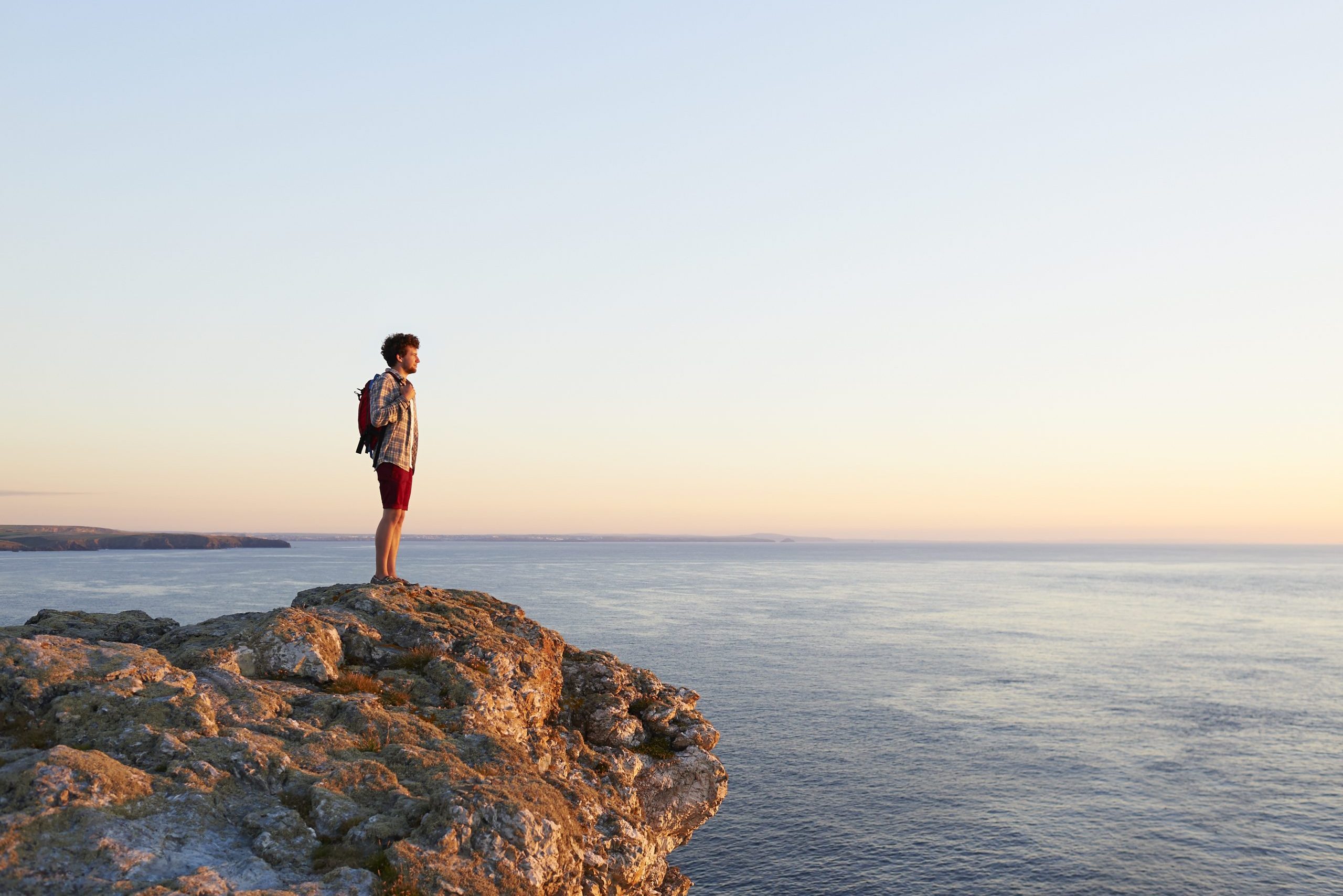 Hiker standing on rock and looking out to sea.