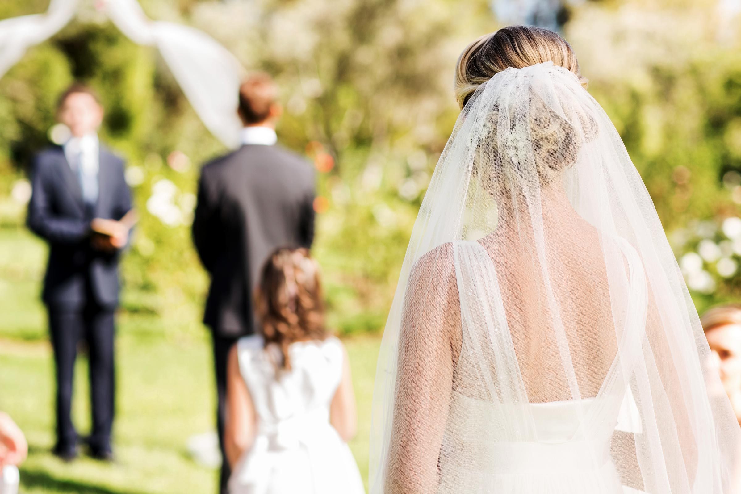 woman in veil walking down the aisle to groom outside