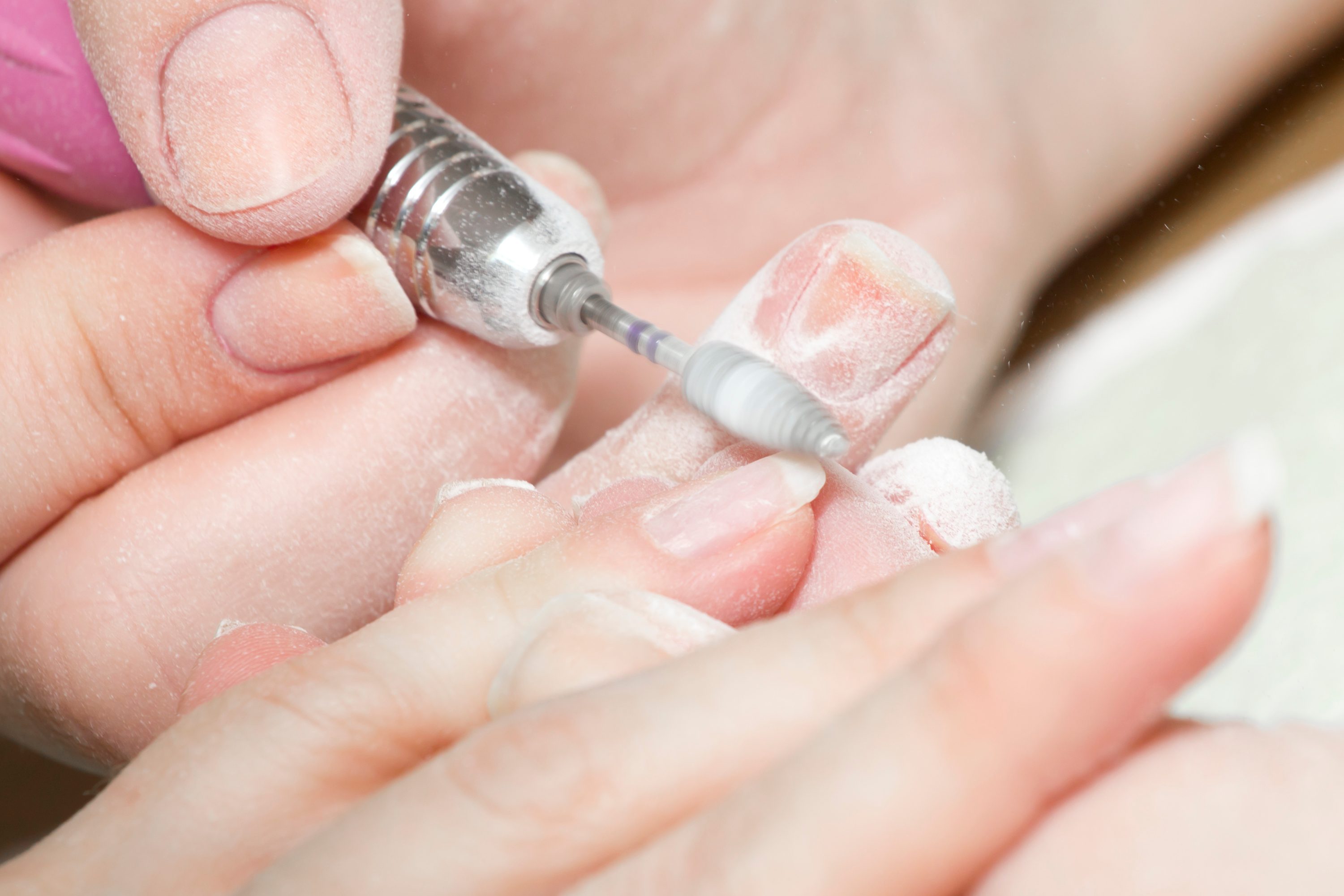 woman nail grinding with electric tool