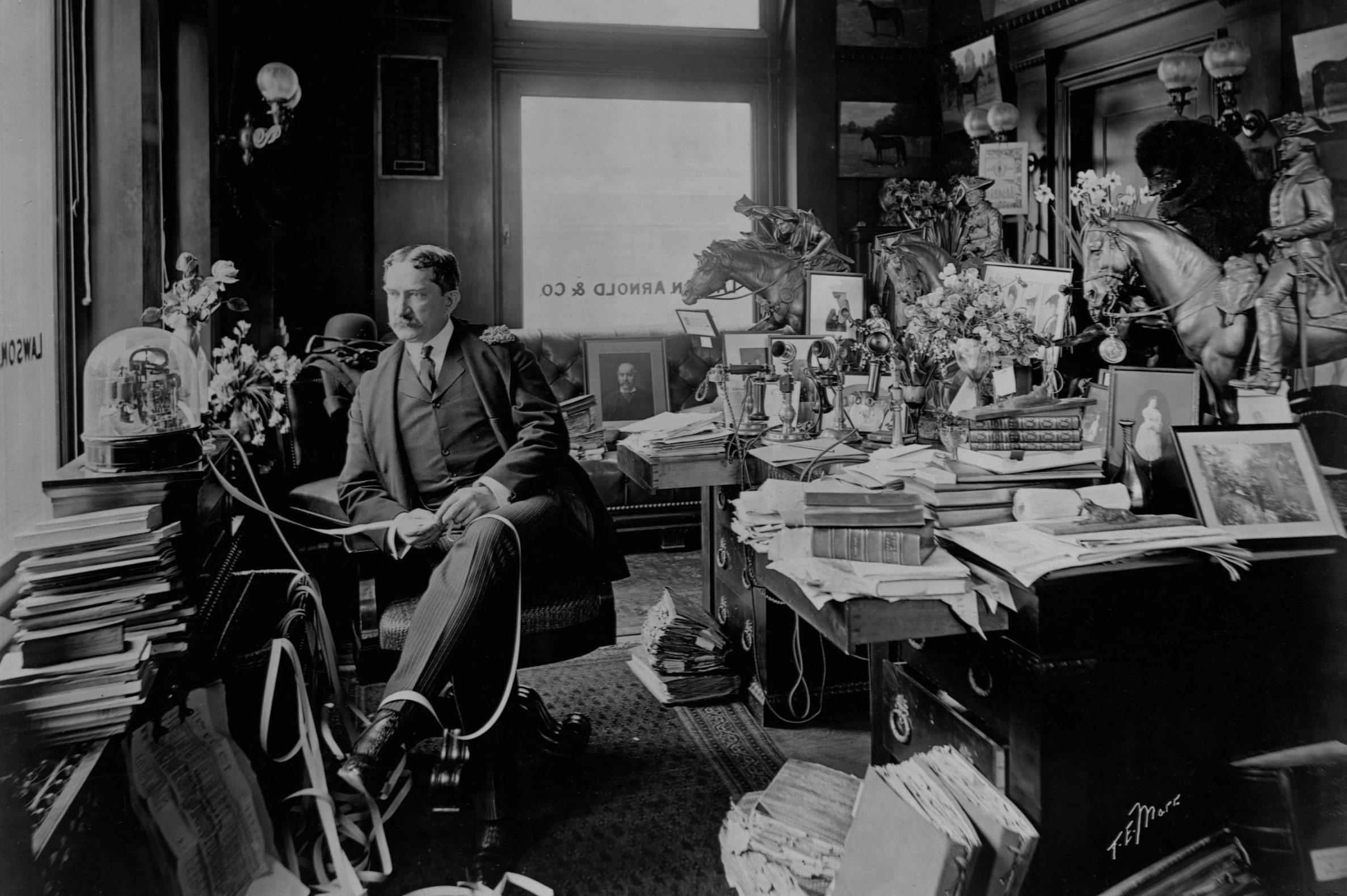 Stockbroker Thomas William Lawson seated in front of a ticker tape machine.