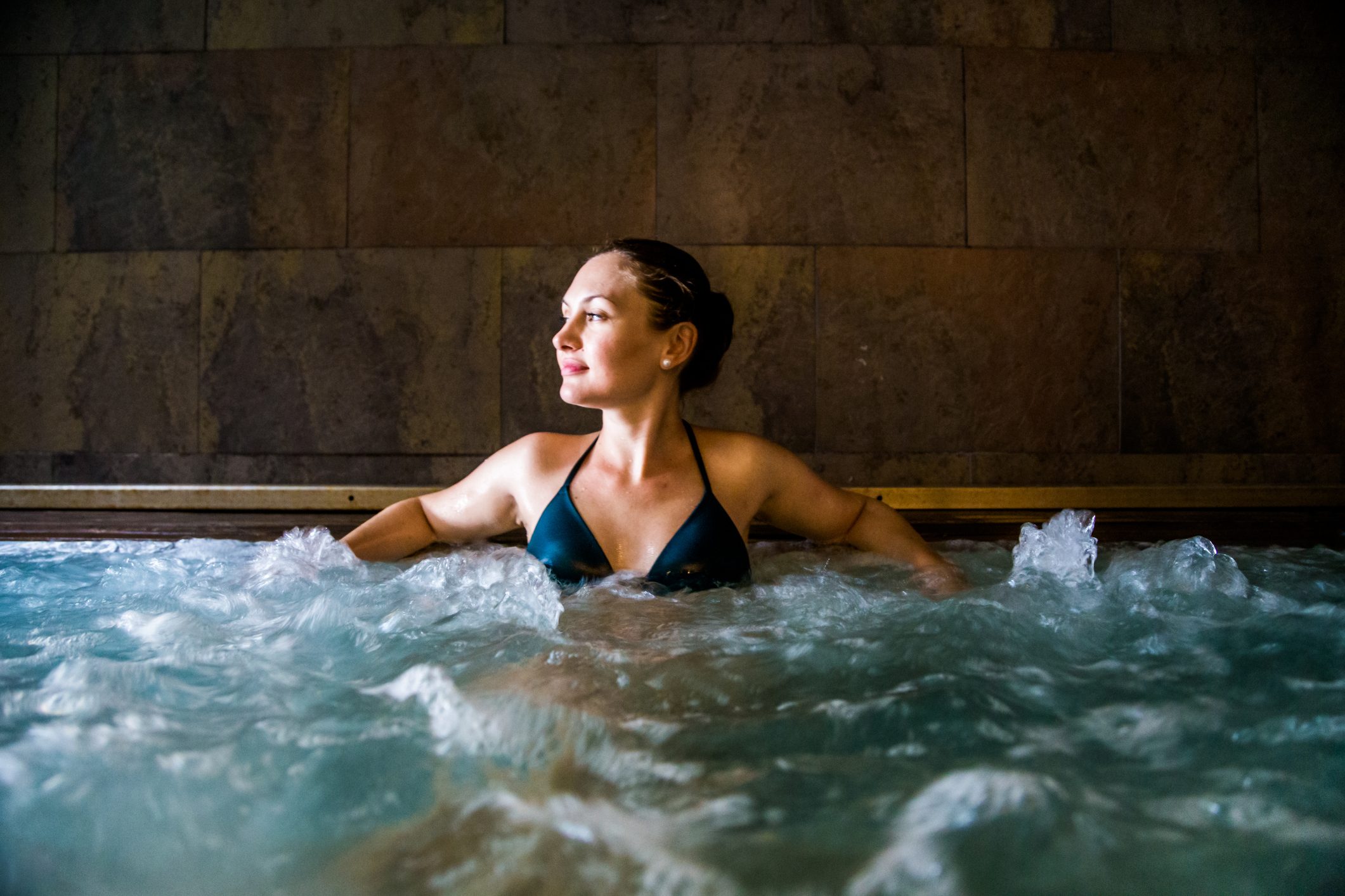 Woman relaxing in a hot tub pool during weekend days of relax and spa in a luxury place during travel vacations.