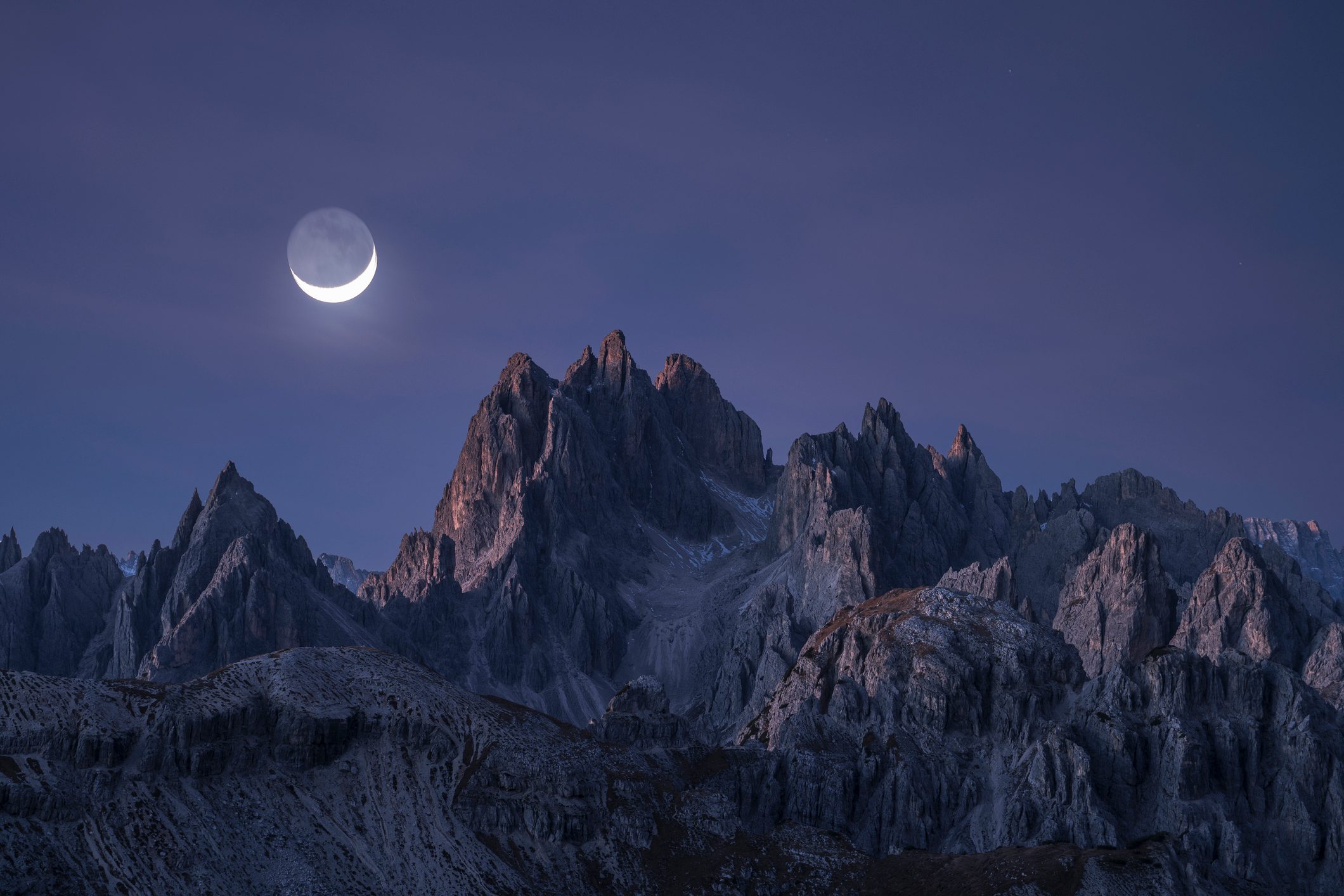 Half moon shining over rocky peaks