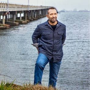 Man standing on the side of a bridge near water