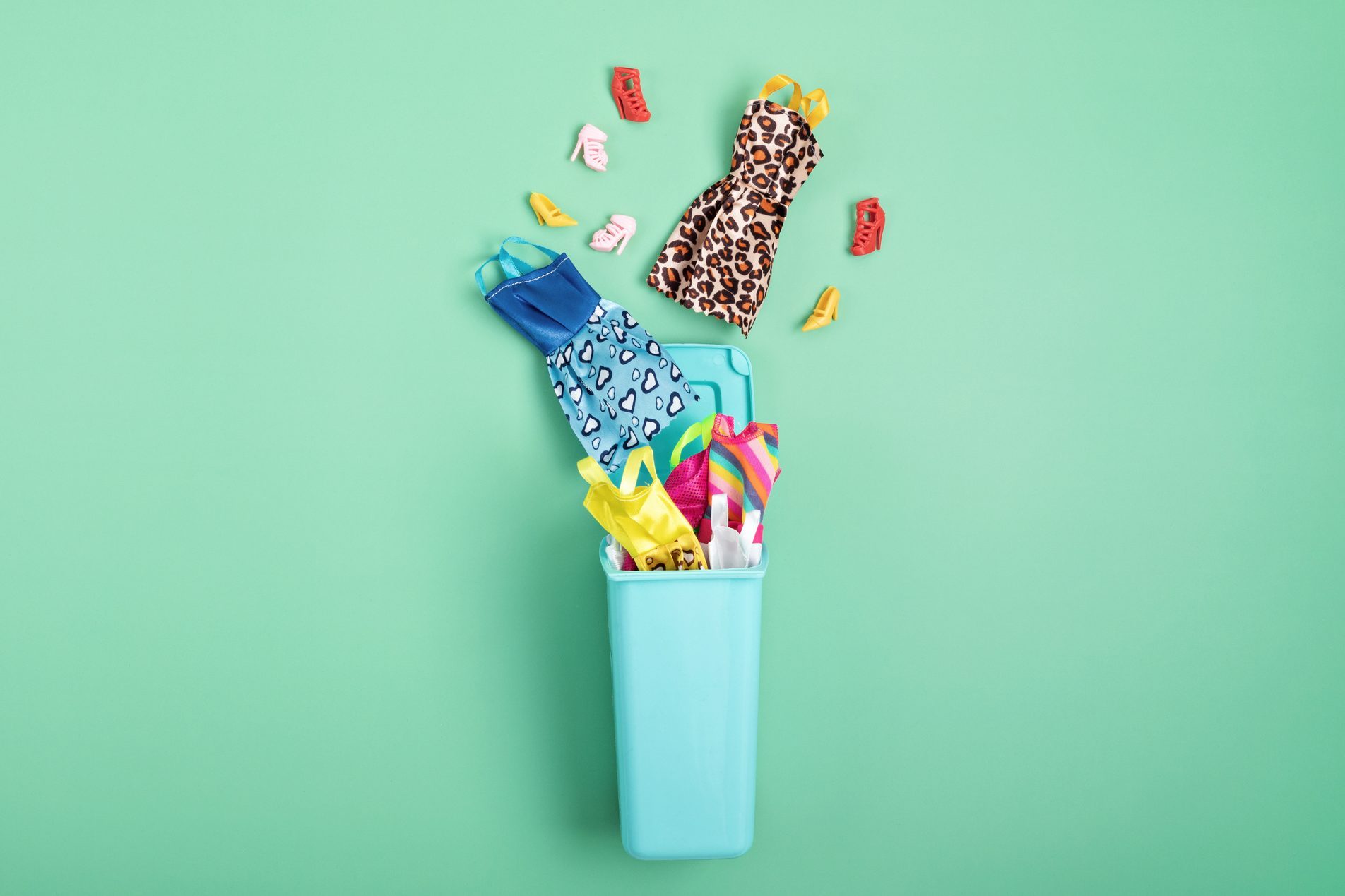 Dresses and shoes in trash bin. Mass fashion, recycling, ethical consumption idea